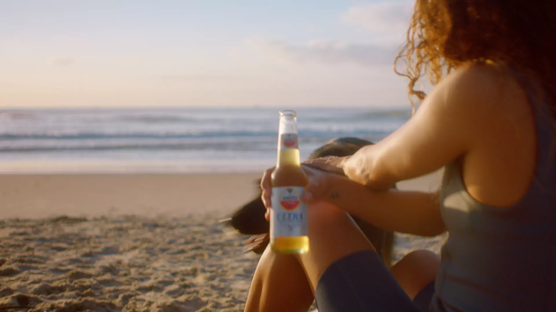 Mulher tomando uma Amstel Ultra na praia